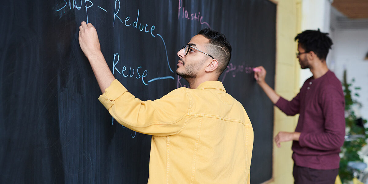 Men writing reduce, reuse, recycle on board. Men writing reduce, reuse, recycle on board.