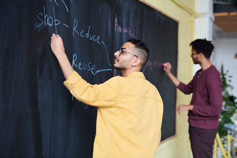 Men writing reduce, reuse, recycle on board.