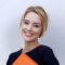 Smiling woman holding orange notebook.