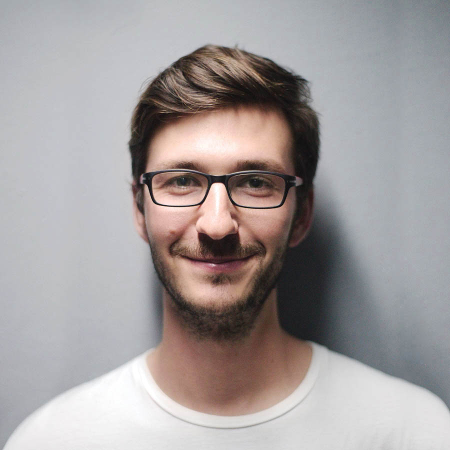 Smiling man wearing glasses and white shirt.