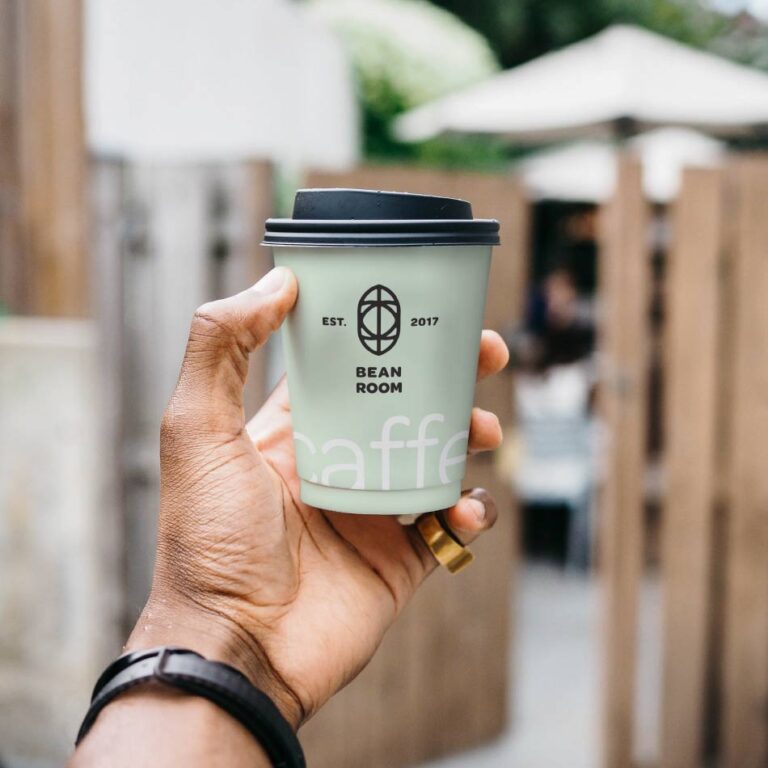Here's an alt text option: Hand holding Bean Room coffee cup.