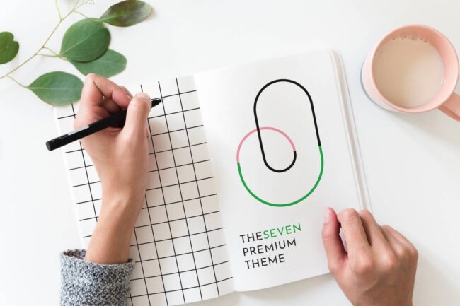 Person writing in grid notebook, TheSeven theme.